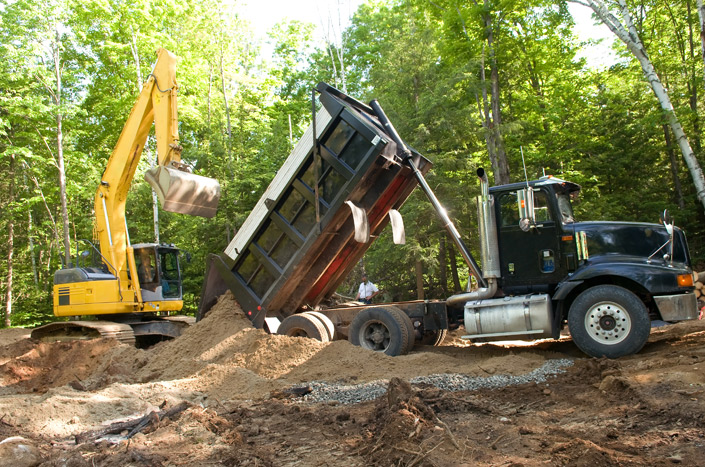 Excavator unloading sand from a truck